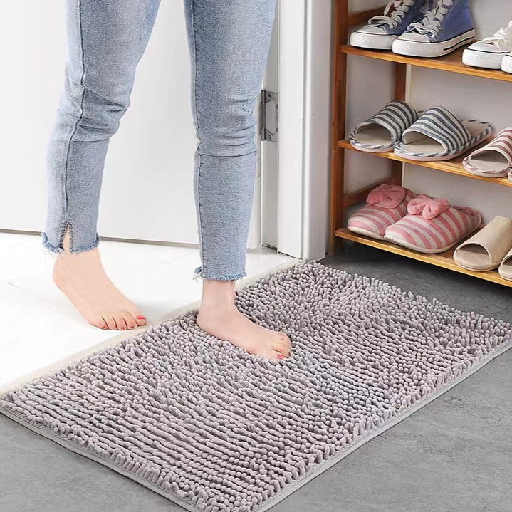 Person stepping onto a gray rug with shoes and slippers on a shelf in the background.